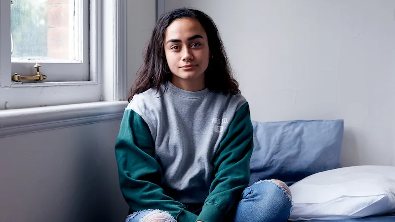 Young woman sitting on bed PC