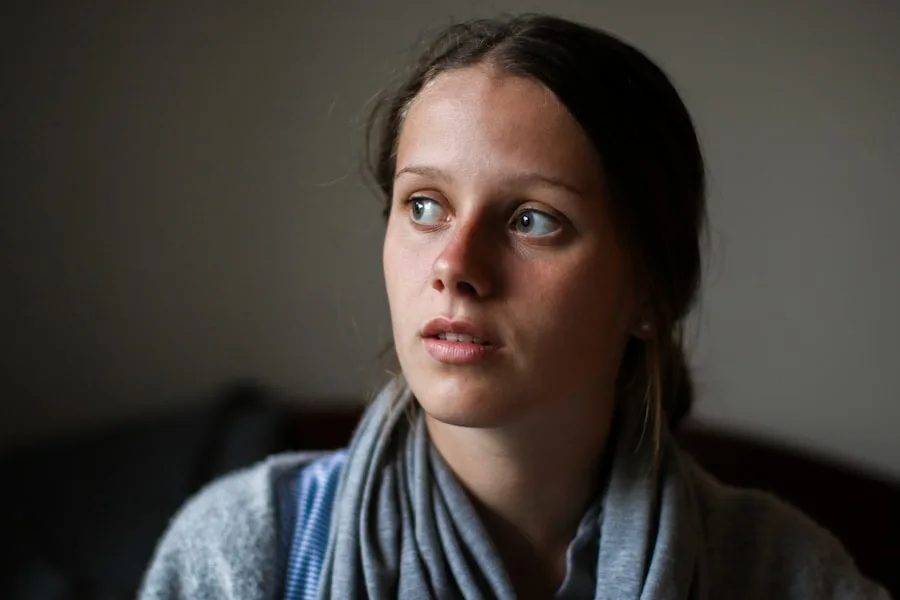 young woman curiously looking out window