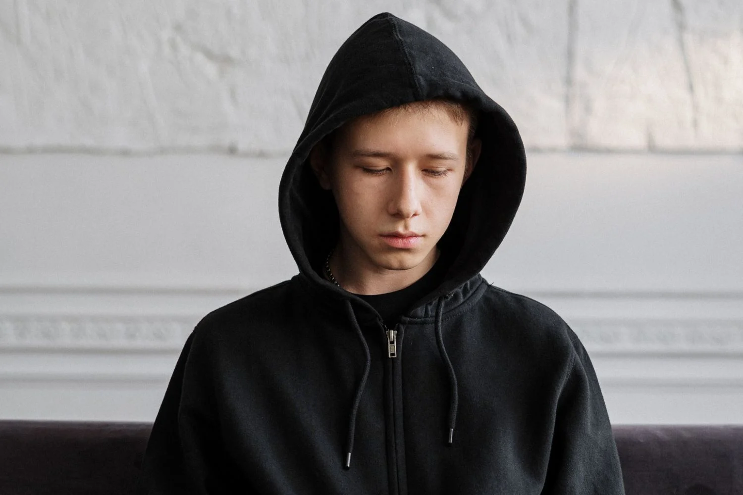 Teen boy in black hoodie looking sad