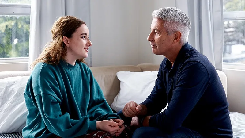 father and daughter talking to each other on couch