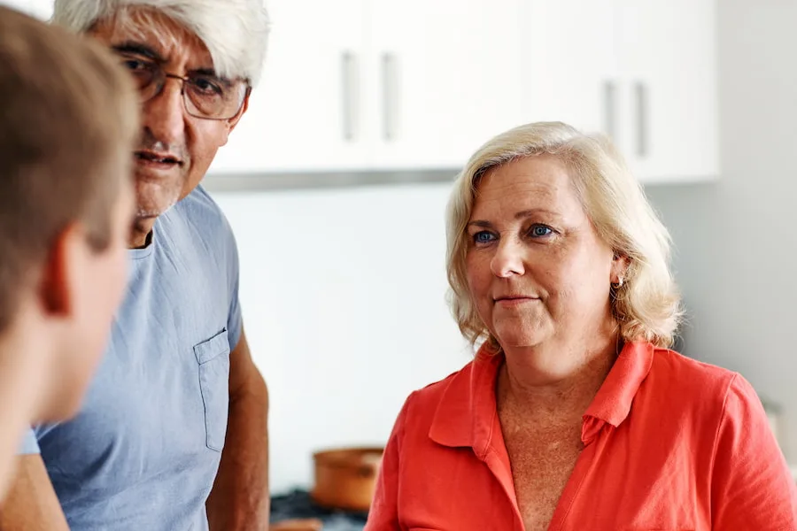 Image of a white mother and father talking to their son in a kitchen.