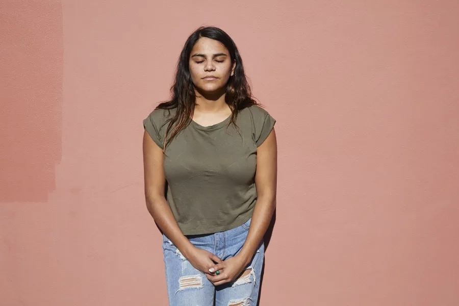 girl leaning against wall with eyes closed