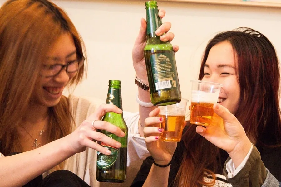 Beer bottles and plastic cups full of beer in toast