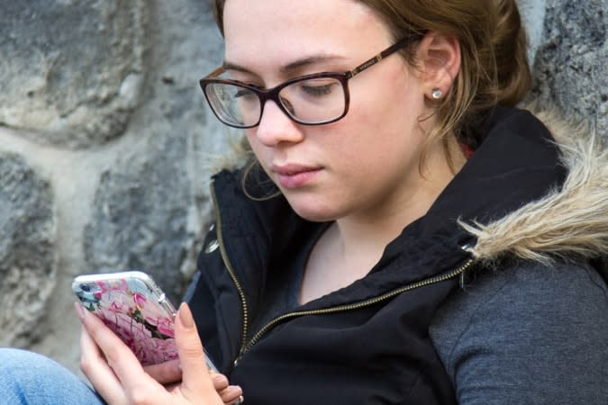 girl sitting down looking at her phone
