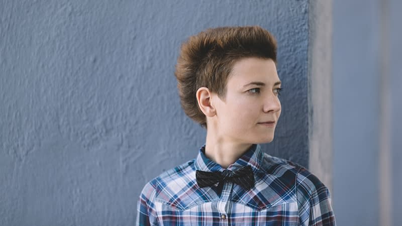 a person wearing a shirt and bow tie in front of a wall, looking to the side