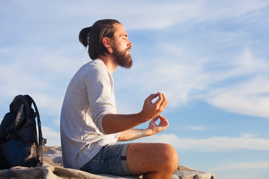 A man sitting cross-legged, meditating with his eyes closed.