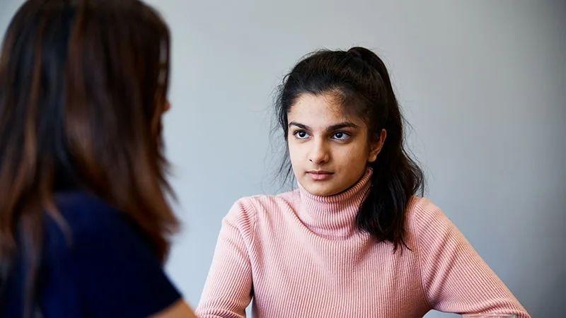 young girl talking at table with her mum