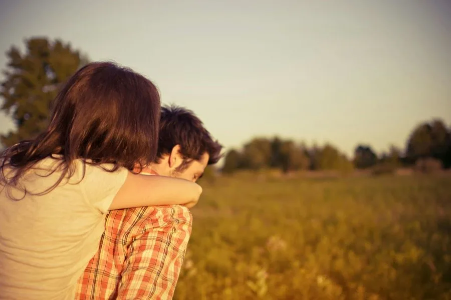 girl and guy facing away in an open field