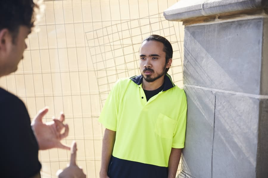 A person in a high-visibility shirt listening to another person. 