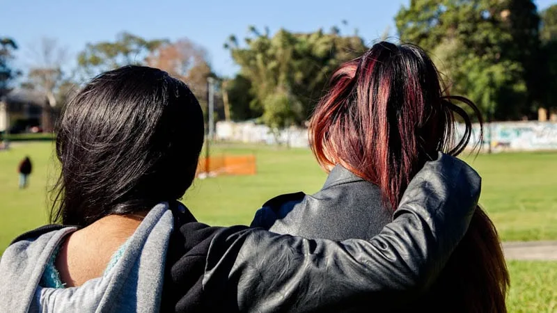 View from behind of girl with arm around girl