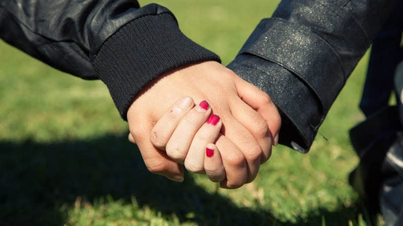 Close up of girls holding hands in park