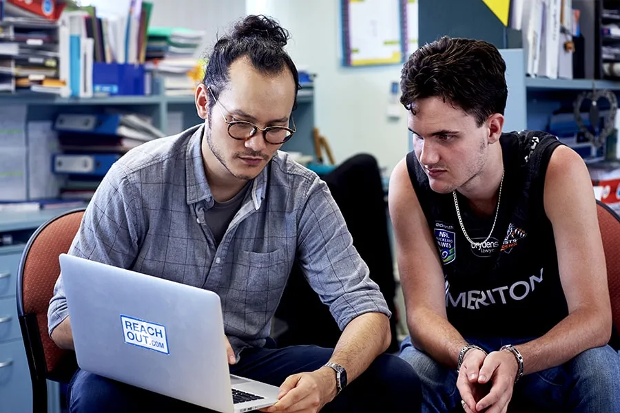 Youth worker showing computer to teenager