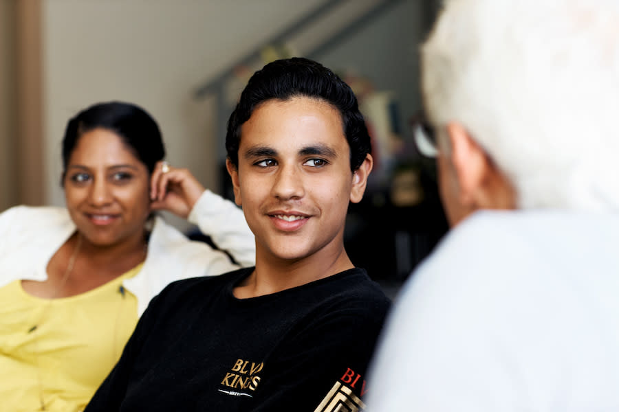 Image of a teen boy sitting on the lounge with his mother and father.