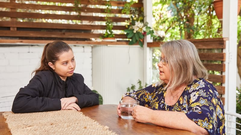 a young person and their parent chatting on a patio