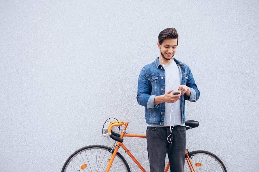 guy using his phone standing in front of a bicycle