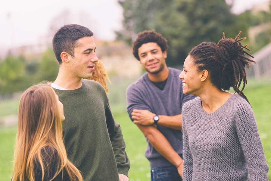 group of young people smiling and talking in park