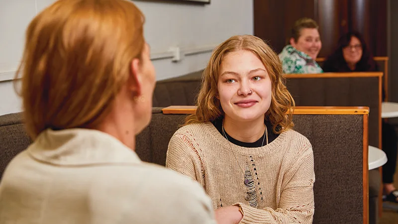 teenage girl chatting with mum at cafe