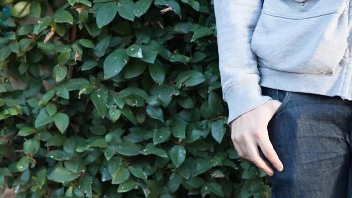 Close up of guys hand in pocket leaning against vines