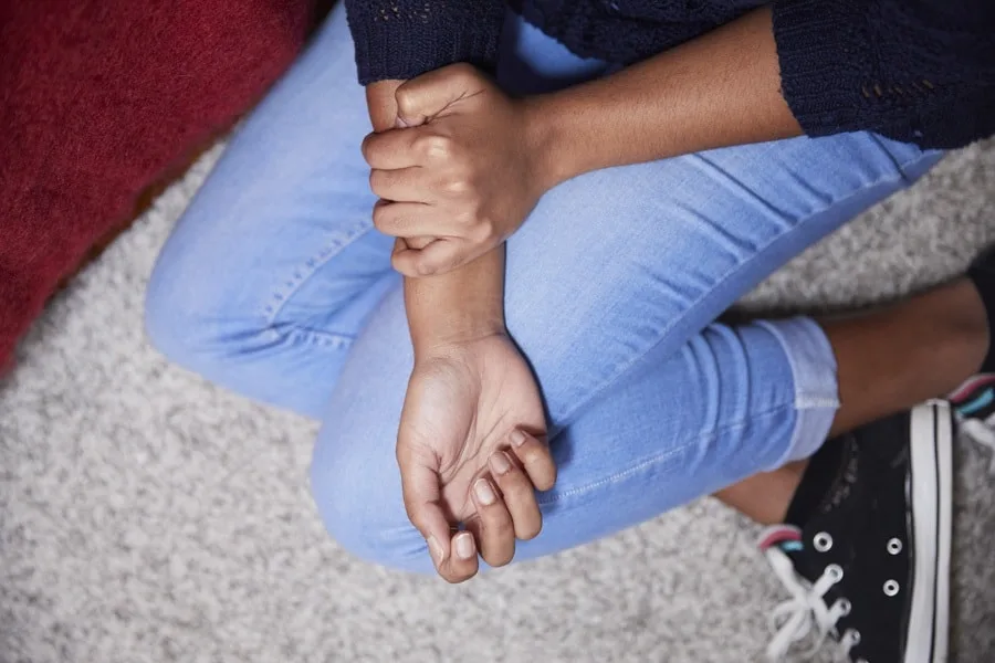 Girl with light wash jeans holding arm