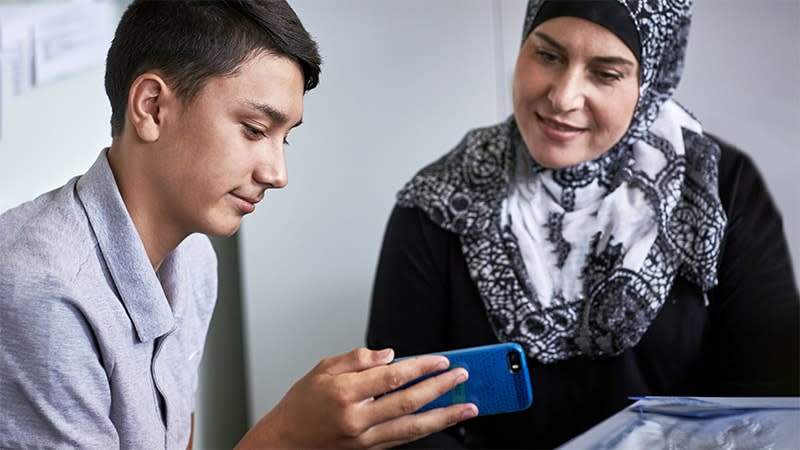 Boy looking at phone with adult