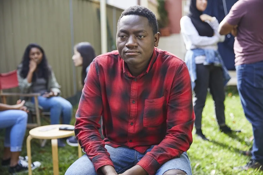 Boy sitting in group looking sad