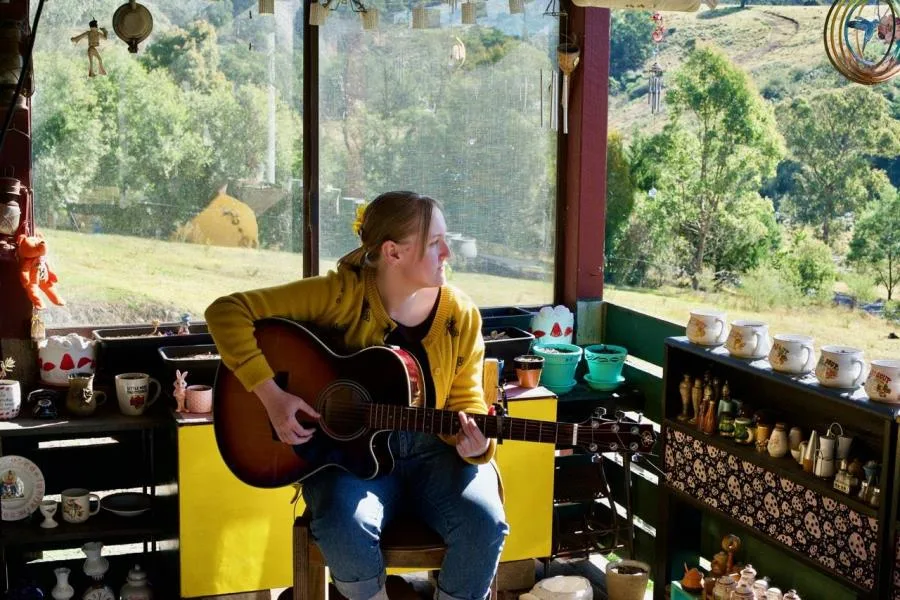 young woman in the bush playing guitar