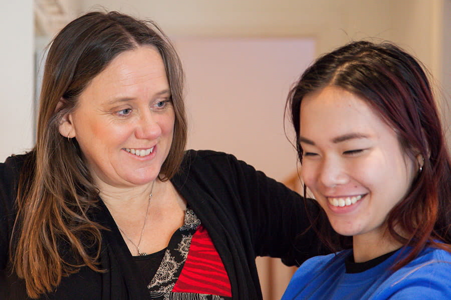 Image of a mother and daughter laughing in kitchen.