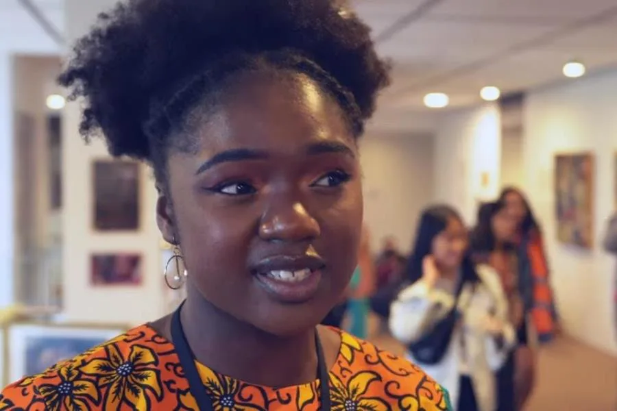 headshot of girl speaking to the camera with young people in the background