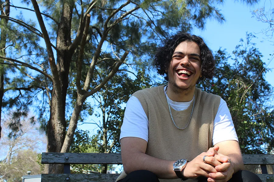 Alex Peisley sitting outside on a park bunch laughing