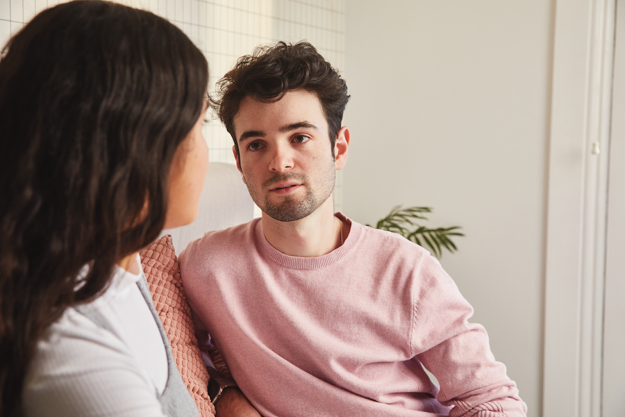 Young man sitting with young woman on couch