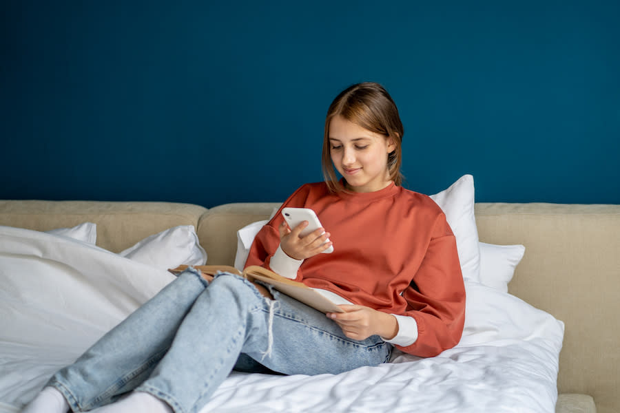 Image of a teen girl scrolling on her phone in her bed.