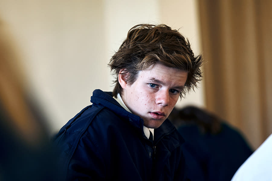 Image of a teen boy at school. He is looking at the camera and seems concerned.