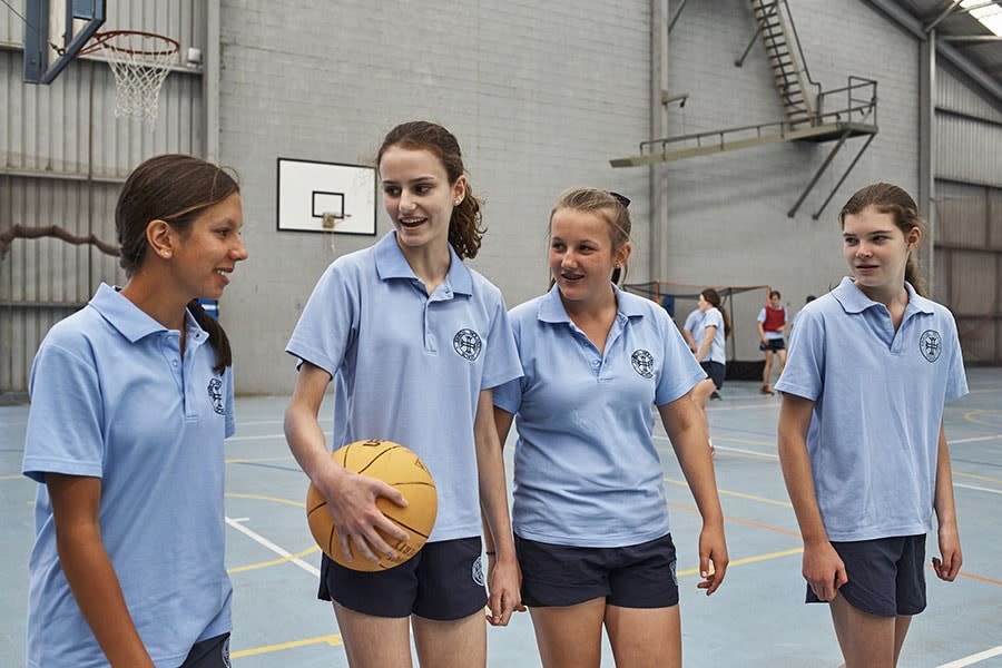 Four school students playing netball in school gym