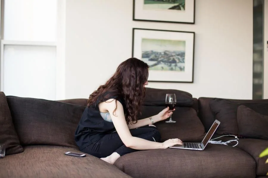 girl on laptop holding wine