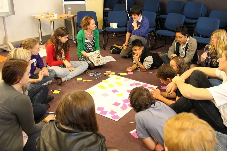 Group students in workshop with teacher in green sweater