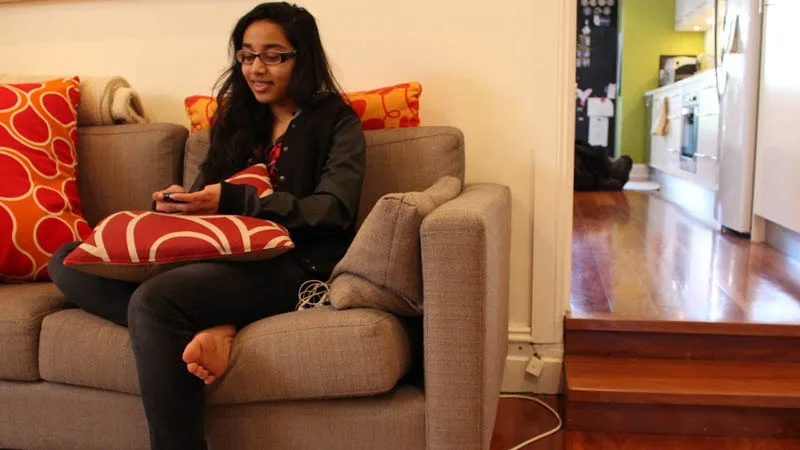 girl sitting on couch using mobile smiling