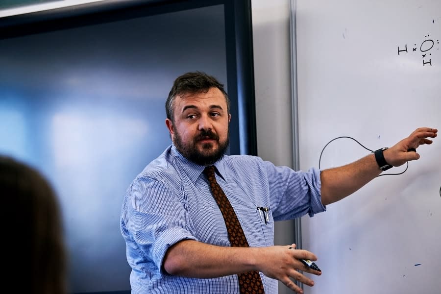 teacher stands at whiteboard teaching class