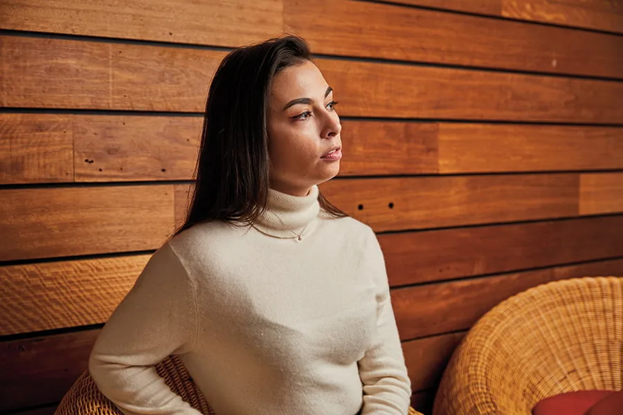 Image of a teenage girl siting outside and looking away from the camera.