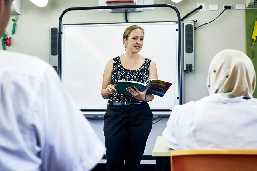 Teacher with geography textbook teaching class