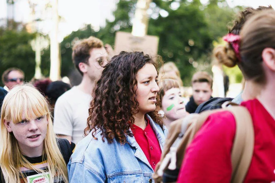 A group of young people marching in a protest, some holding signs in the background.