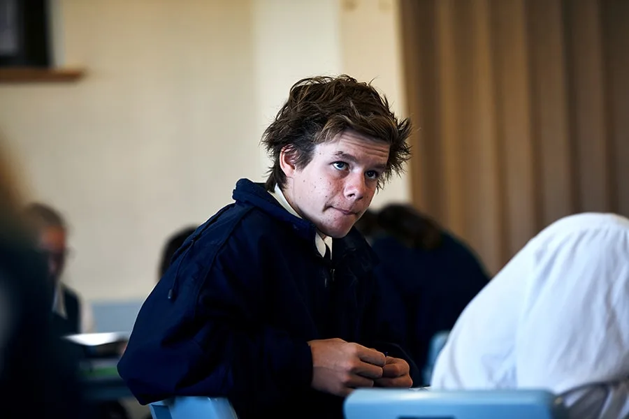 school boy sitting in class with neutral expression