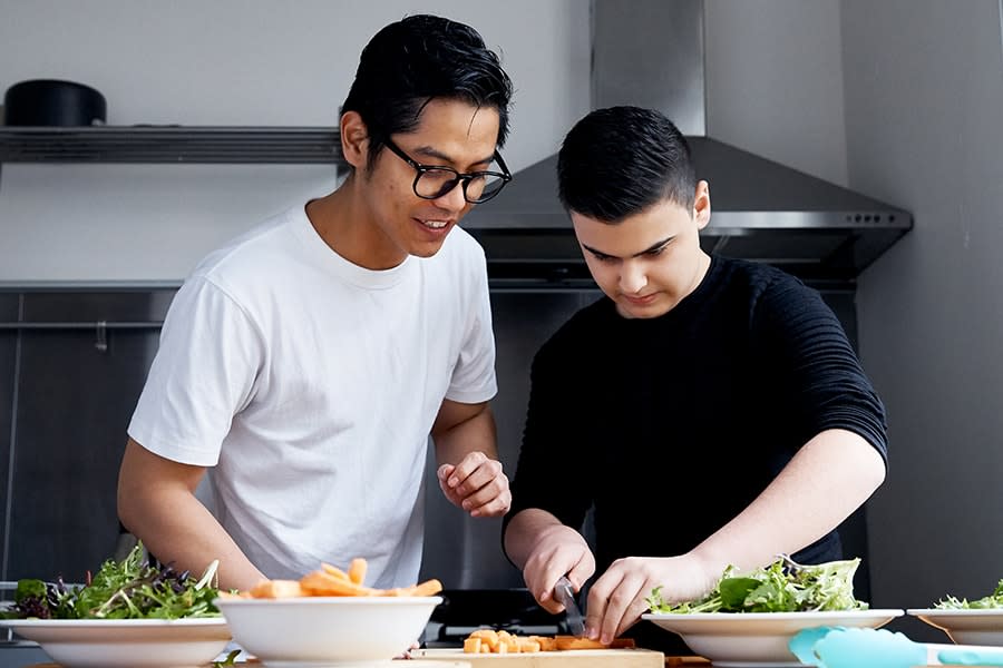 two guys in their late teens chopping vegetables