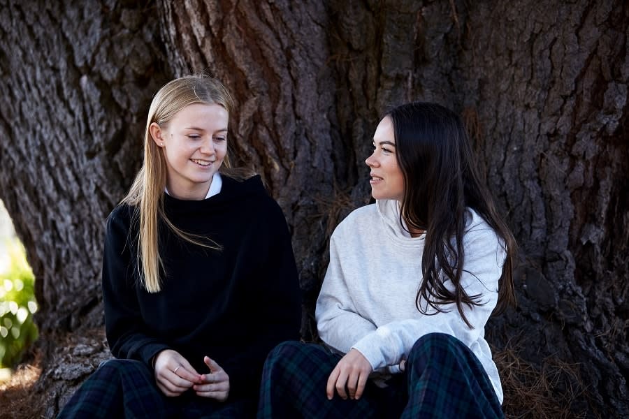 two girls talking next to tree