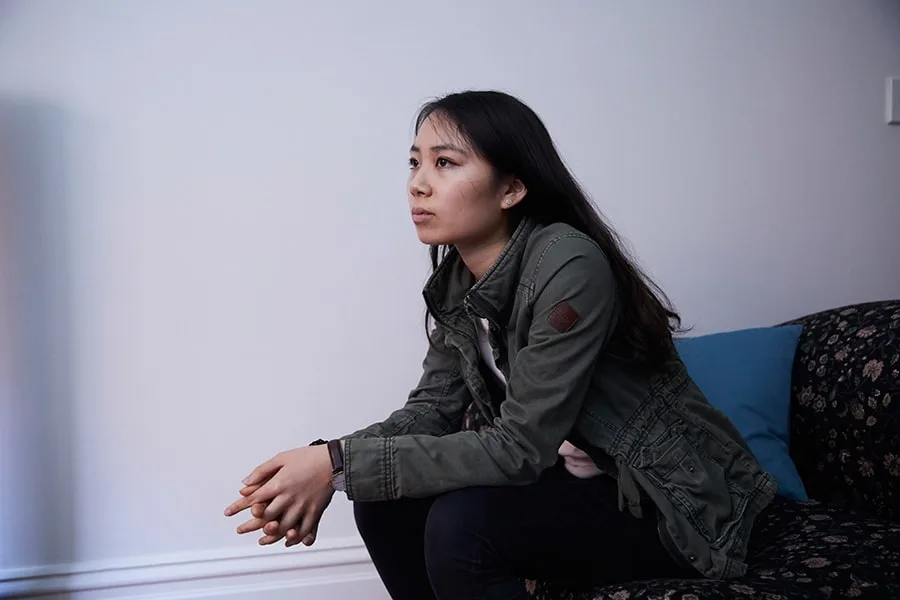 Girl sitting down with hands clasped