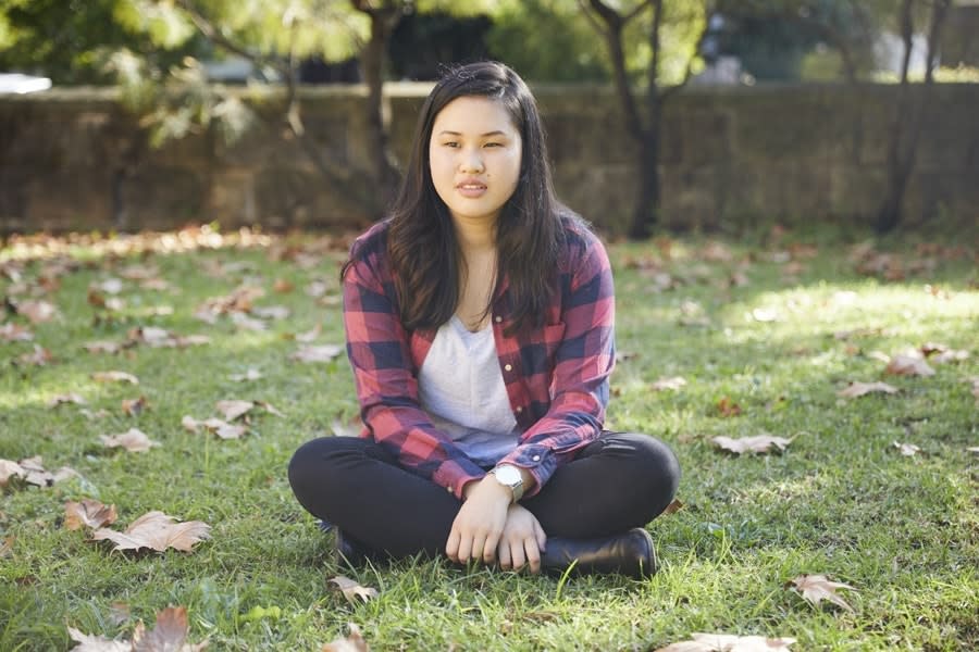 Girl in red checked shirt sitting in park