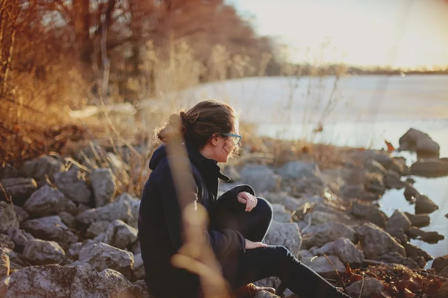 Girl sitting on rocks next to water