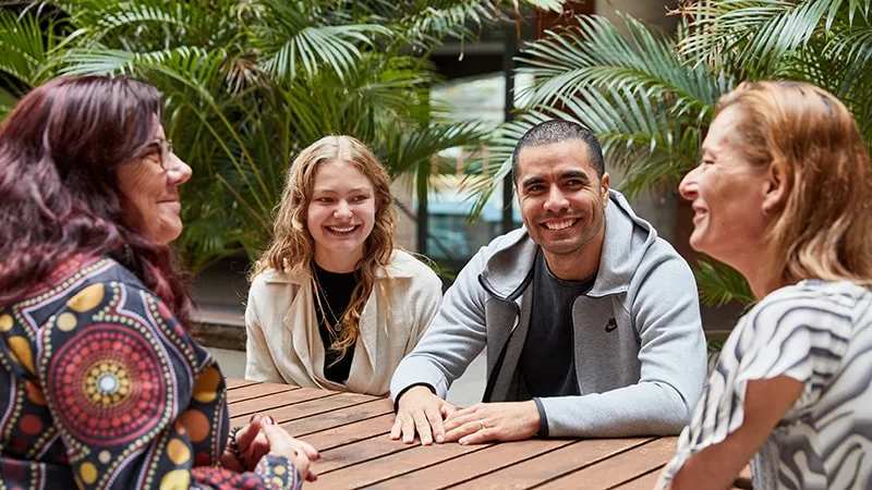 three aboriginal and torres strait islander parents carers smiling and talking to one young person