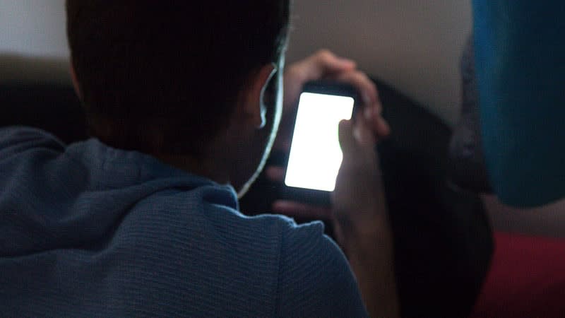 Young male using phone in dark