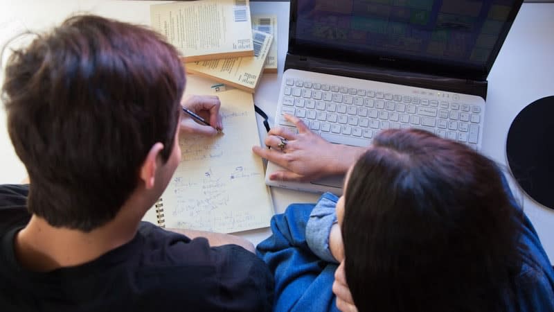 Aerial view of guy and girl studying with notes and laptop
