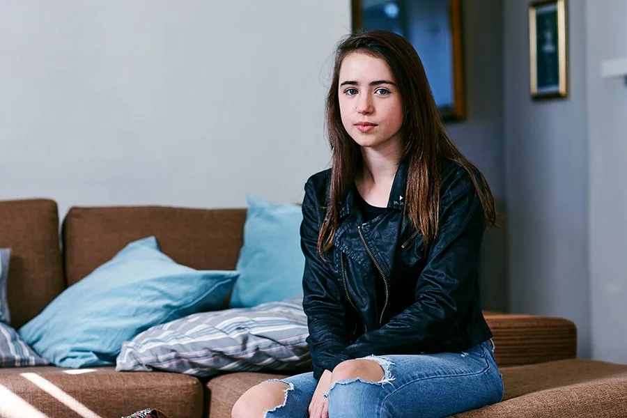 girl sitting on couch in living room looking at camera